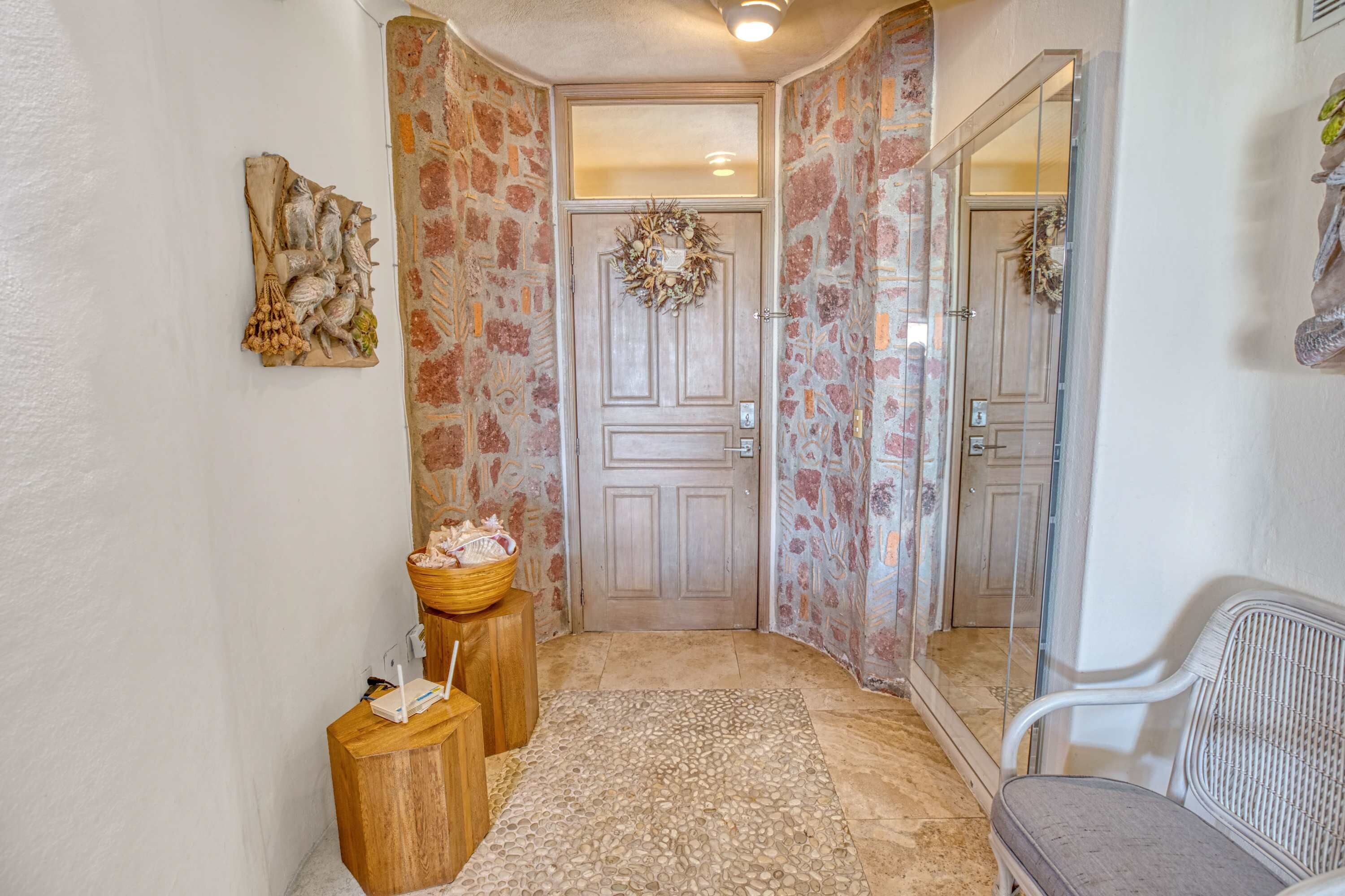 Un pasillo con un banco de madera, un tapete y una puerta decorada con un adorno floral.