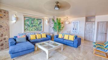 A living room with a sectional sofa, a glass coffee table, and a potted plant.