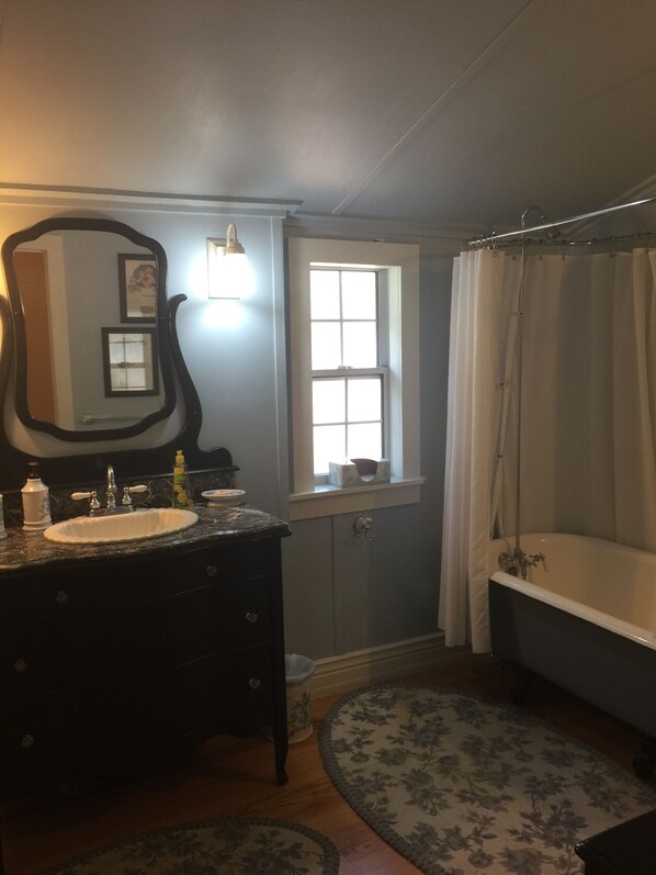 A bathroom with a sink, mirror, window, and bathtub. - Victorian House Downtown (Prescott)