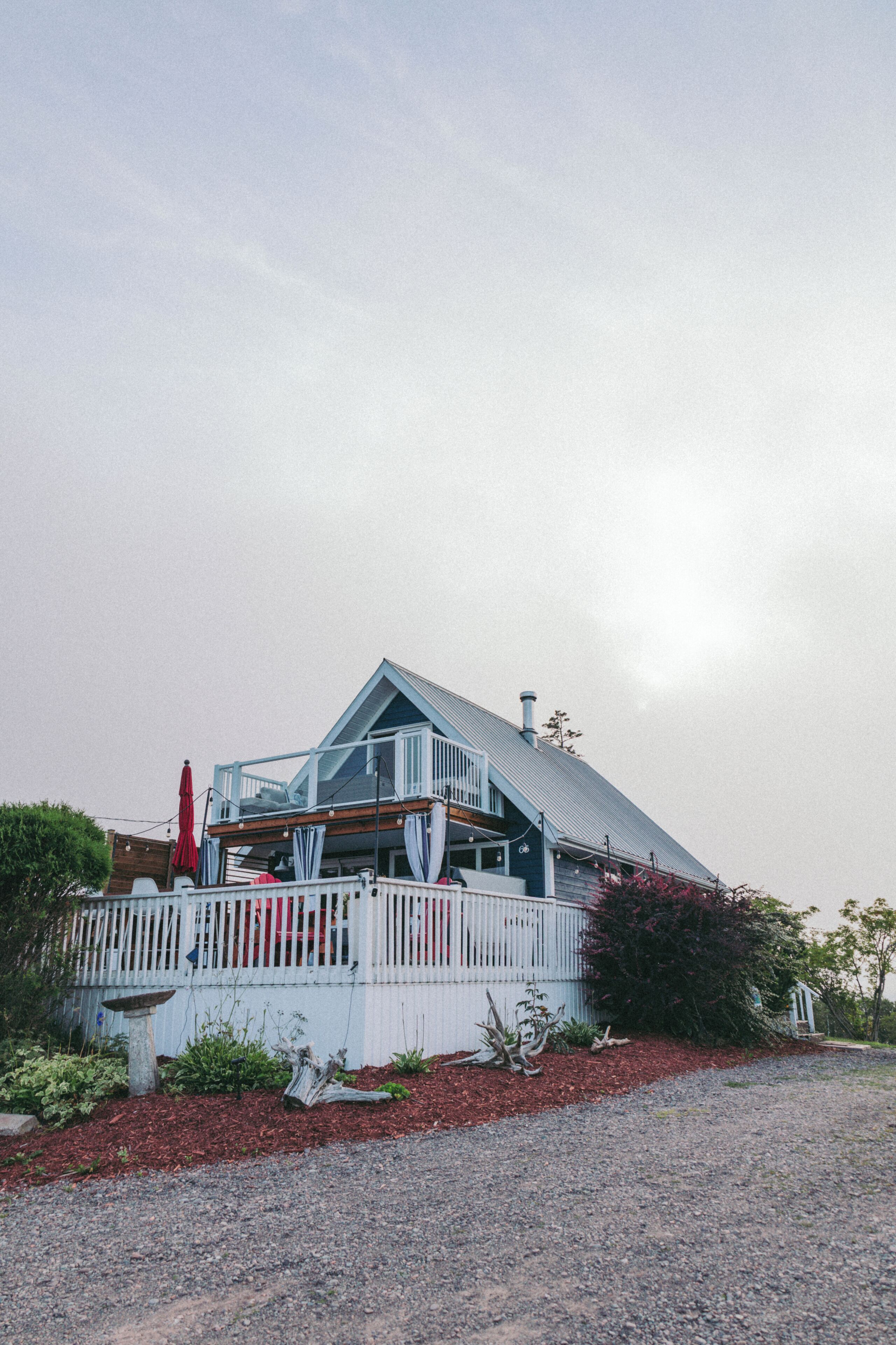A house with a sloped roof, a balcony, and a fenced yard.