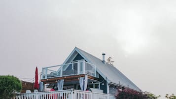 A house with a sloped roof, a balcony, and a fenced yard.