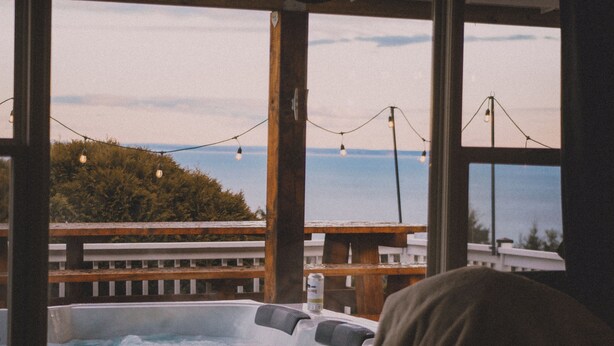 Een hottub met uitzicht op zee, sfeerverlichting en een houten terras.