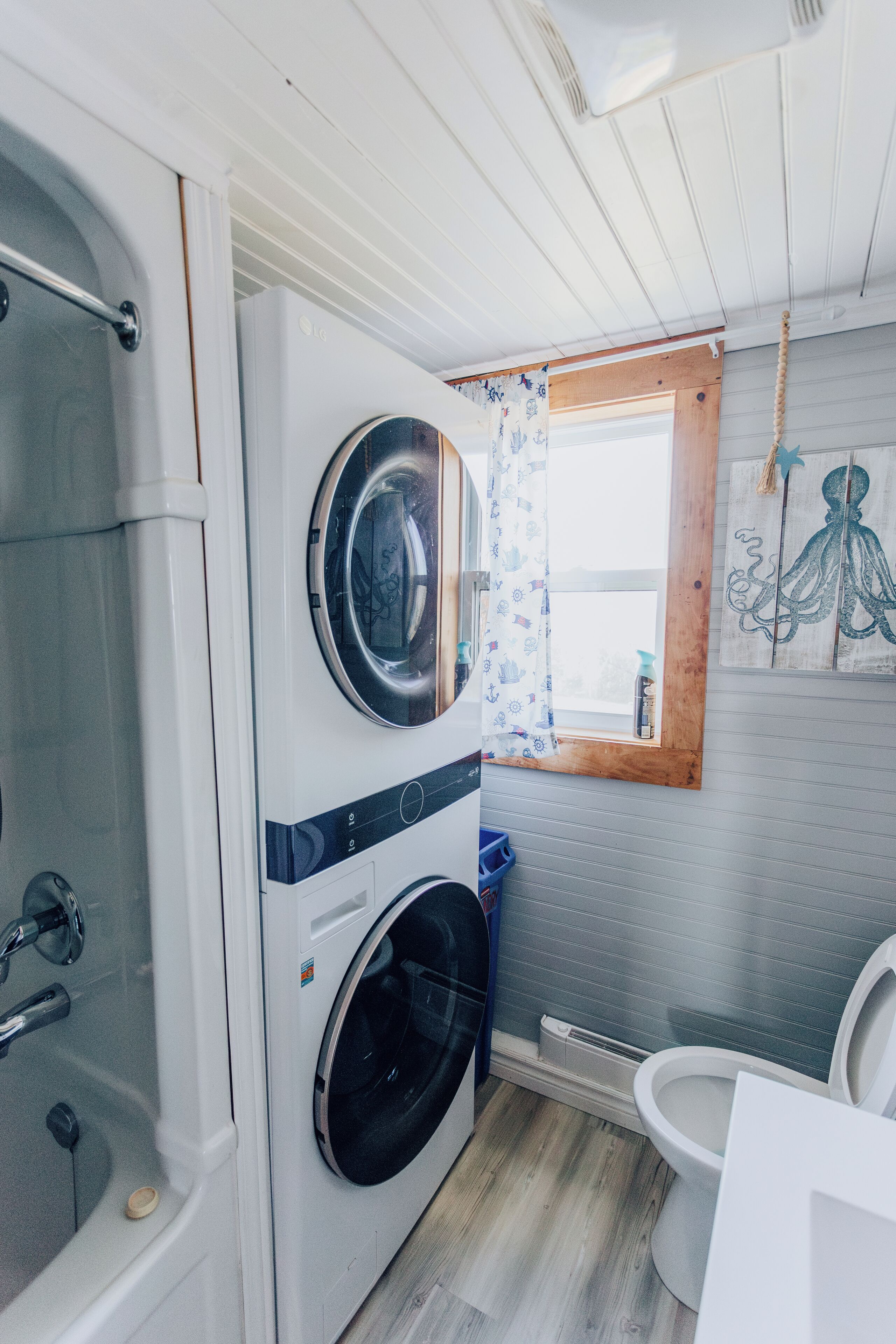 Une petite salle de bain équipée d’un lave-linge, d’une baignoire et de toilettes.