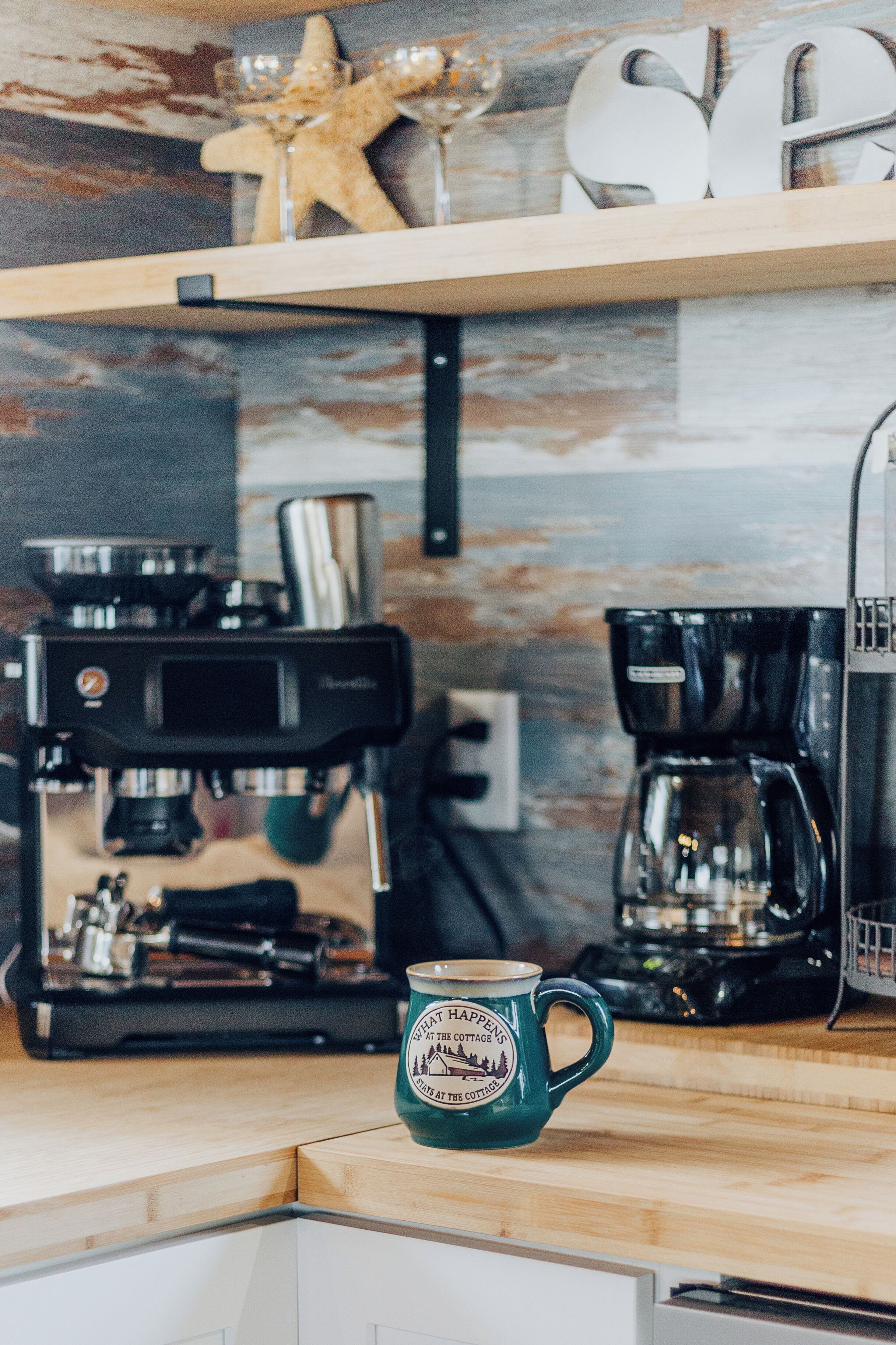 Een keuken met een koffieapparaat, een mok en een zeester decoratie op de plank.