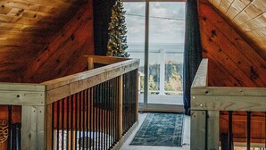 A wooden interior with a sloped ceiling, a staircase leading to a balcony, and a Christmas tree. - Ocean View • Hot Tub • Pet-Friendly Coastal Retreat (Parrsboro)