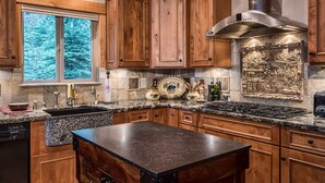 A kitchen with wooden cabinets, a granite countertop, a stainless steel range hood, and a decorative backsplash.