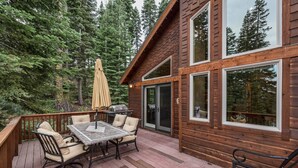 A wooden deck with a table and chairs, a grill, and a patio umbrella.