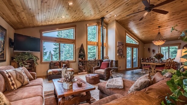 A spacious living room with a high ceiling, large windows, and a fireplace.
