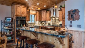 A kitchen with wooden cabinets, a granite countertop, and pendant lighting.