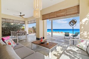 Amplia sala de estar con una mesa de centro de madera, un sofá y vista a la playa.