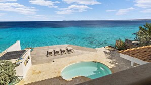 Ein Poolbereich mit Blick auf das Meer, Liegestühle und eine Holzterrasse.