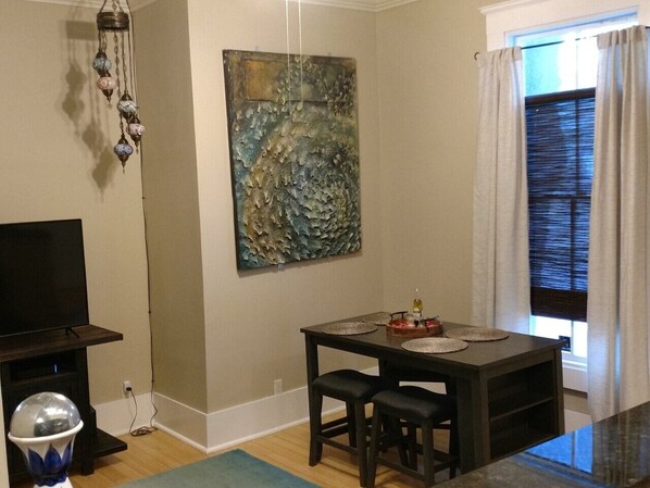 A dining area with a table, chairs, a television, and a decorative wall piece. - Cozy 2bdrm / 1 bath Condo in the walkable Starland Area of Savannah (Savannah)