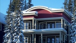 A multi-story building with a red facade, balconies, and snow-covered surroundings.