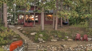 A cabin with a stone staircase leading to a deck, surrounded by trees and a small pond. - Classic Minnesota Cabin on Beautiful Lake O'Brien - Includes Pontoon Boat (Crosslake)