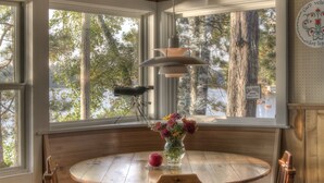 A wooden dining table with chairs, a hanging pendant light, and a vase with flowers. - Classic Minnesota Cabin on Beautiful Lake O'Brien - Includes Pontoon Boat (Crosslake)