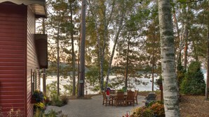 A cabin with a paved deck, outdoor seating, and a sign indicating a campsite. - Classic Minnesota Cabin on Beautiful Lake O'Brien - Includes Pontoon Boat (Crosslake)