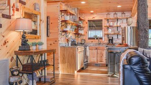 Eine gemütliche Küchenzeile im Chalet-Stil mit Holzwänden, einer Mittelinsel und einer Barbereich.