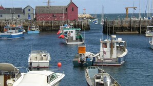 Un puerto con varios barcos amarrados, un edificio rojo y un muelle de piedra.