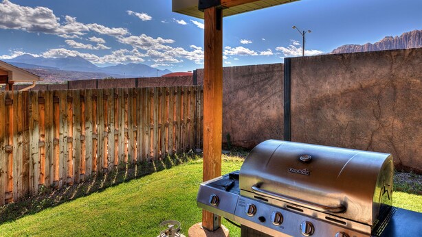Un barbecue orné du logo Char-Broil, une clôture en bois et, en arrière-plan, une vue sur des montagnes.