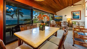 A dining area with a table, chairs, and a view of the ocean. - Beachfront Condo E 303/ Incredible views/ Pickleball/Great Snorkeling (Kihei)