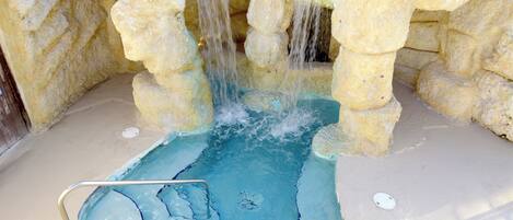 Una piscina con una cascada rodeada de formaciones rocosas.