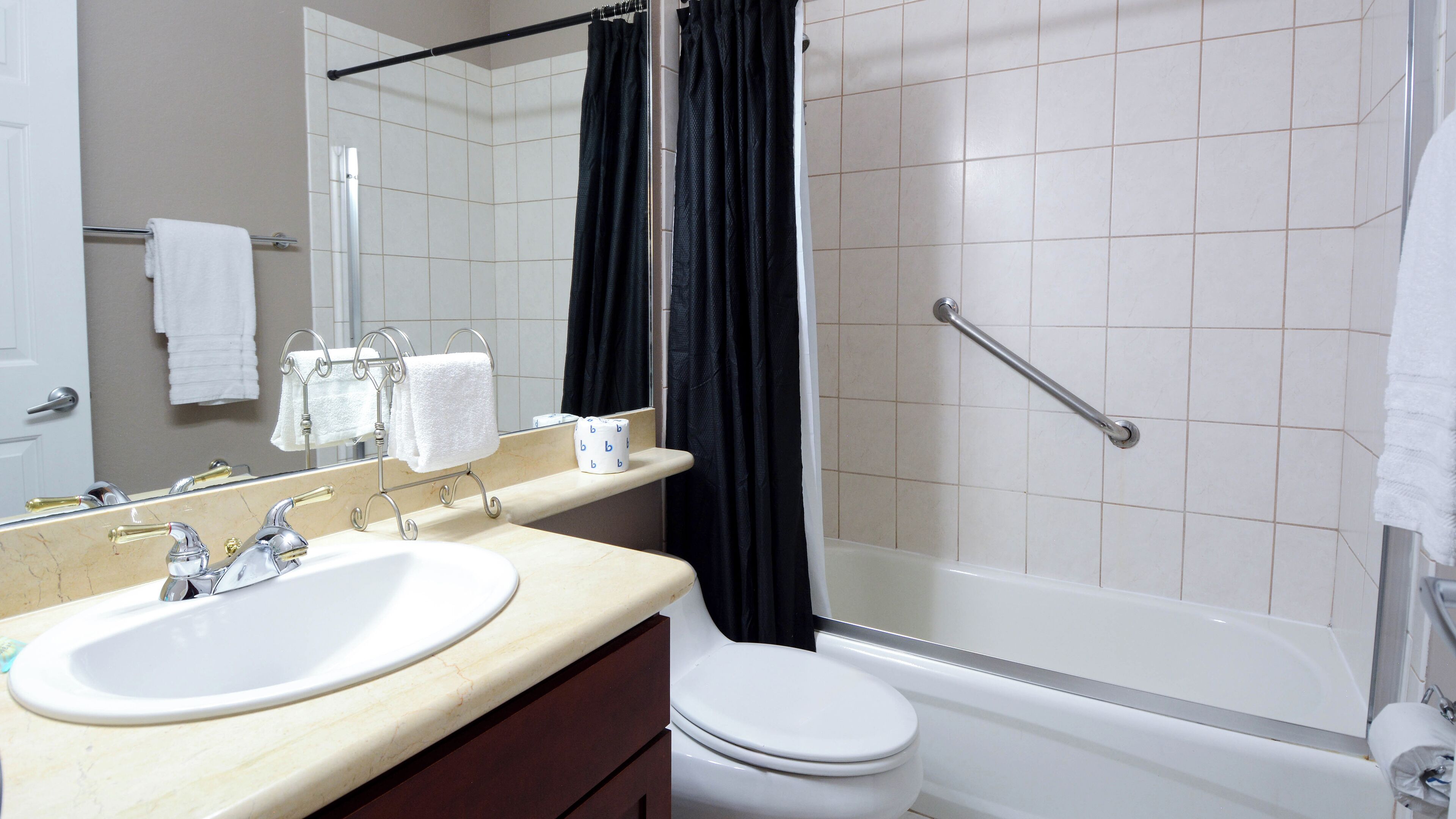 A bathroom with a sink, mirror, toilet, and bathtub.
