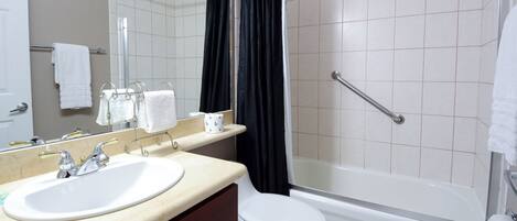 A bathroom with a sink, mirror, toilet, and bathtub.