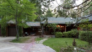 A rustic cabin with a stone pathway leading to a wooden door, surrounded by lush greenery and a well-maintained lawn. - PAPA BEAR'S LODGE -Best Log Cabin in Nevada City Sleeps up to 10.  (Nevada City)