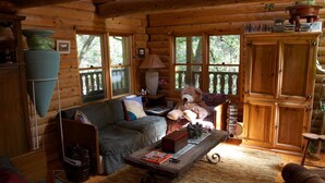 A cozy cabin interior with a wooden log wall, a sofa, a coffee table, and a teddy bear. - PAPA BEAR'S LODGE -Best Log Cabin in Nevada City Sleeps up to 10.  (Nevada City)