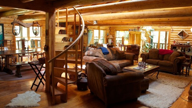 A log cabin interior with a spiral staircase, leather sofas, wooden tables, and a dining area. - PAPA BEAR'S LODGE -Best Log Cabin in Nevada City Sleeps up to 10.  (Nevada City)