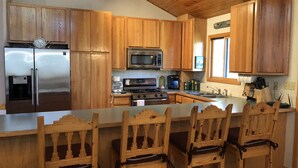 Una cucina con mobili in legno, elettrodomestici in acciaio inossidabile, un forno a microonde, una macchina da caffè e un lavandino.