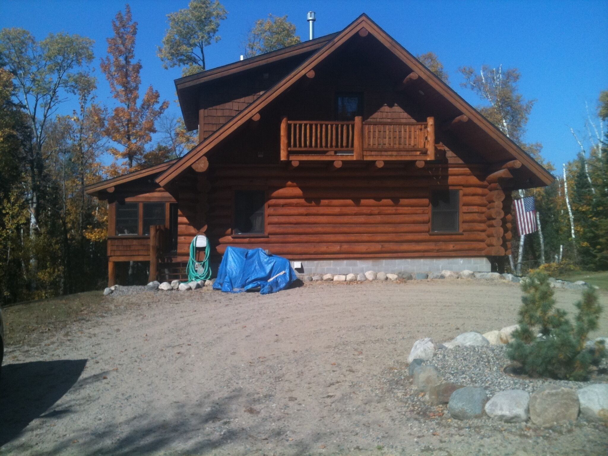 Une cabane en rondins avec un balcon, une véranda et un drapeau.