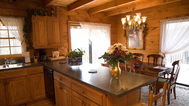 Une cuisine de style rustique, avec des murs en bois, un îlot central, des armoires en bois et un lustre.