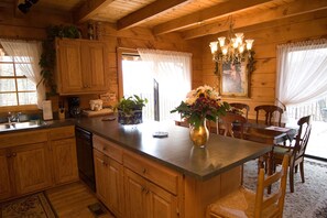 Une cuisine de style rustique, avec des murs en bois, un îlot central, des armoires en bois et un lustre.