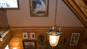 Un salon chaleureux avec une cheminée en pierre, des meubles en bois et un luminaire suspendu.