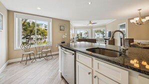 A modern kitchen with a large island, white cabinetry, and a view of the outdoors. - Ocean Front Villa w/ Community Amenities (Hilton Head Island)