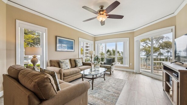A spacious living room with a ceiling fan, large windows, and a view of the outdoors. - Ocean Front Villa w/ Community Amenities (Hilton Head Island)