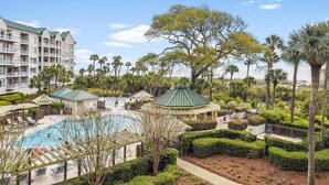 A resort with a swimming pool, multiple buildings, and lush landscaping. - Ocean Front Villa w/ Community Amenities (Hilton Head Island)