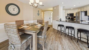 A dining area with a wooden table, wicker chairs, and a wall clock. - Ocean Front Villa w/ Community Amenities (Hilton Head Island)