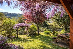 A garden with a wooden pergola, a picnic table, and a view of a valley.