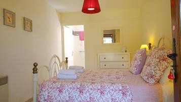 A bedroom with a bed, a dresser, a mirror, and a red hanging light.