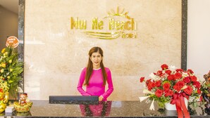 Una reception con un cartello che riporta la scritta "Muu Ne Beach Hotel" e una donna dietro di essa.