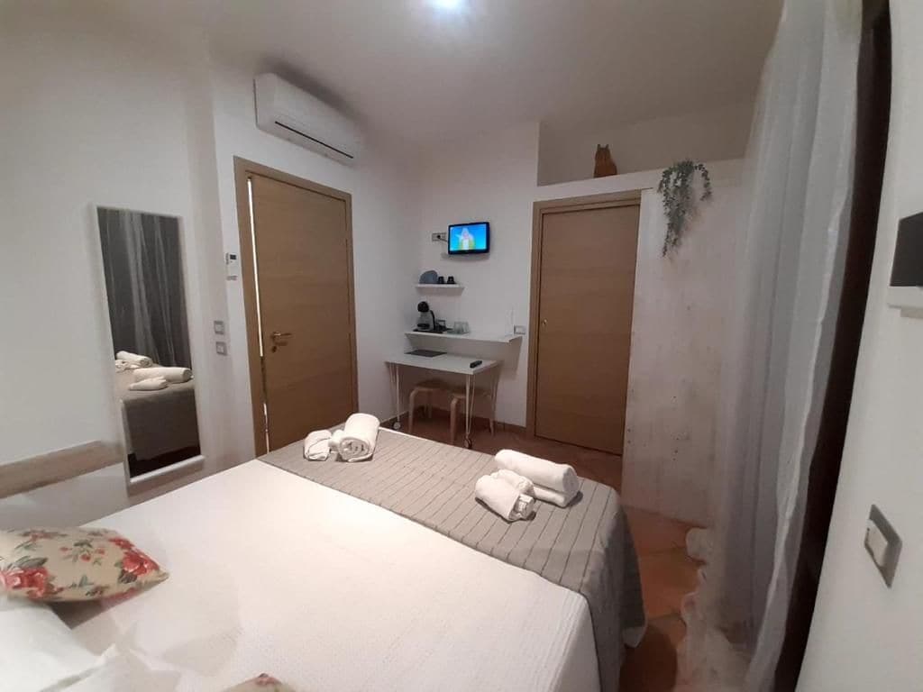 Una camera d'albergo con un letto, una scrivania, una televisione e un bagno.