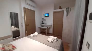 Una camera d'albergo con un letto, una scrivania, una televisione e un bagno.