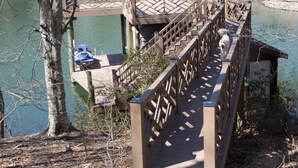 Eine Holzbrücke über einem Gewässer, auf der ein Hund entlanggeht.