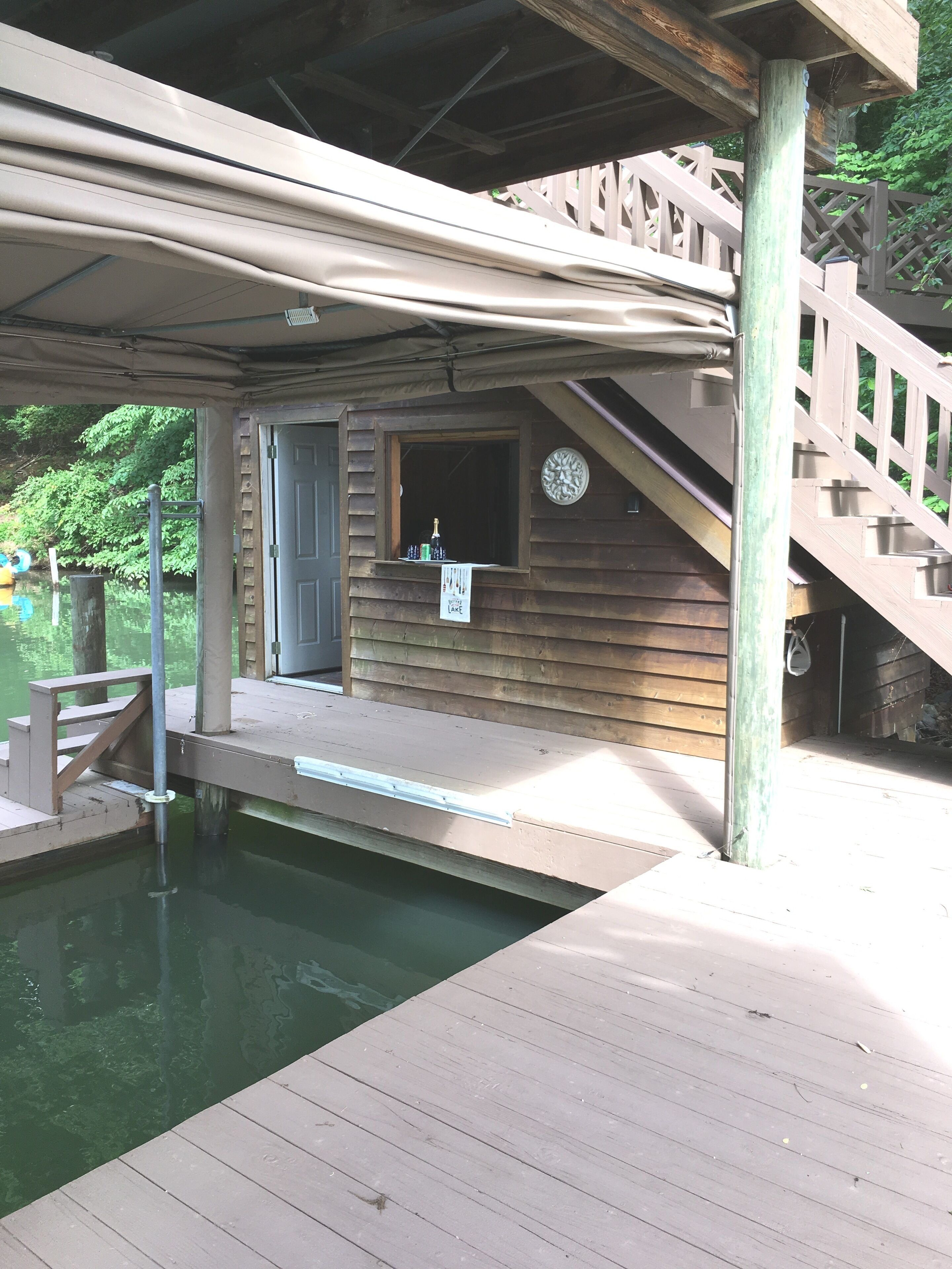 A wooden cabin with a small pool, a wooden staircase, and a window with a sign.