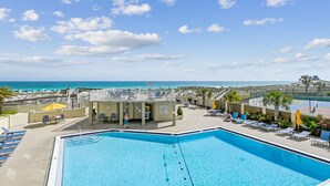 A swimming pool with lounge chairs and a view of the ocean.