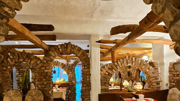 A rustic dining area with stone arches and wooden beams, featuring tables set for dining. - Apartments Atomis Hotel Düsseldorf City (Düsseldorf)