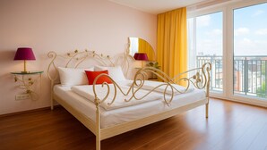 A neatly made bed with white linens and a red pillow, a gold-framed headboard, and a bedside table with a purple lamp. - Apartments Atomis Hotel Düsseldorf City (Düsseldorf)