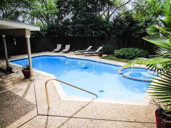 A backyard with a swimming pool, lounge chairs, and a covered patio area. - Escape it all! Private pool/hot tub. Top location! (San Antonio)